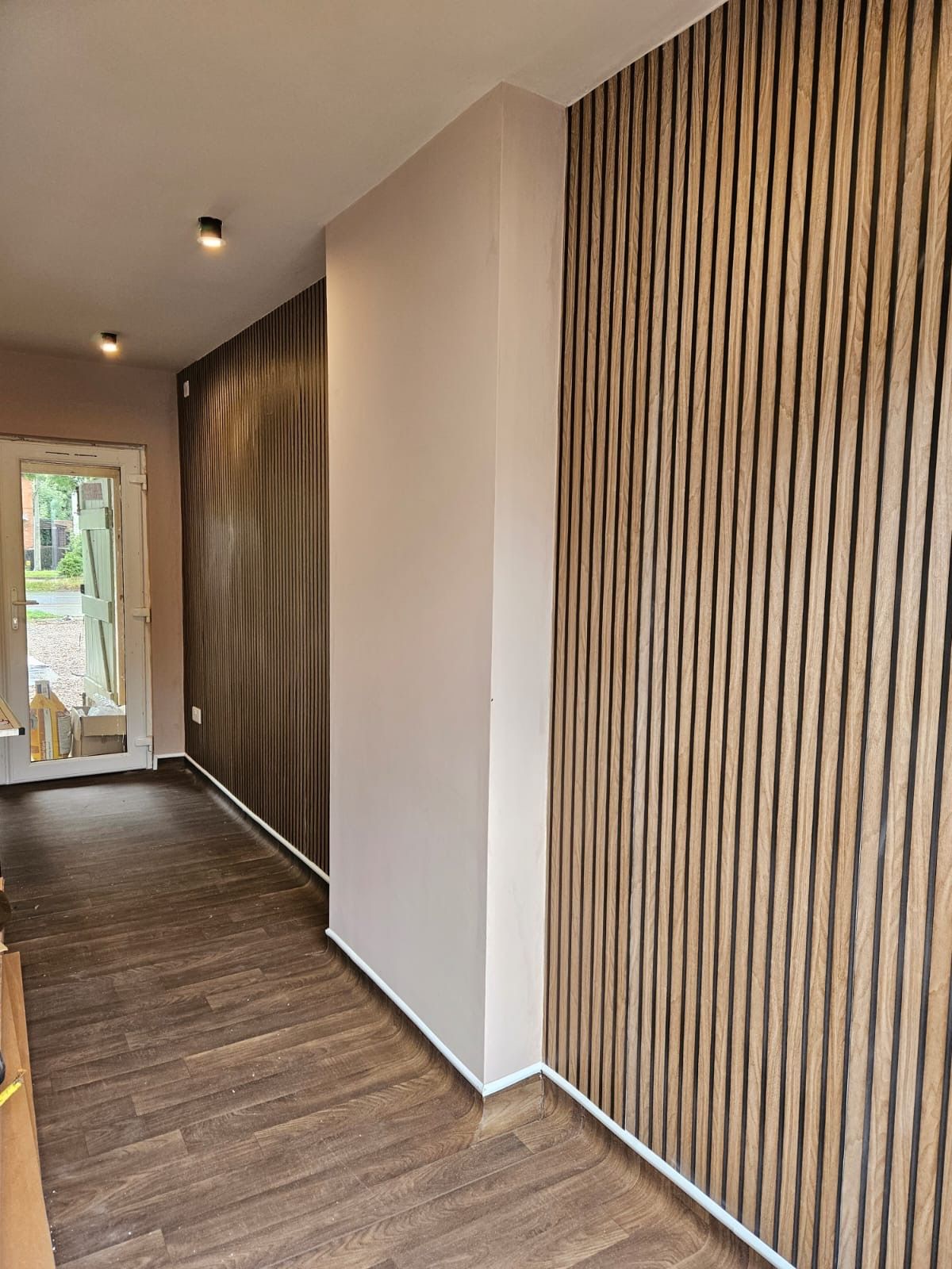 A wall with wood-slat wallpaper and pink paint.