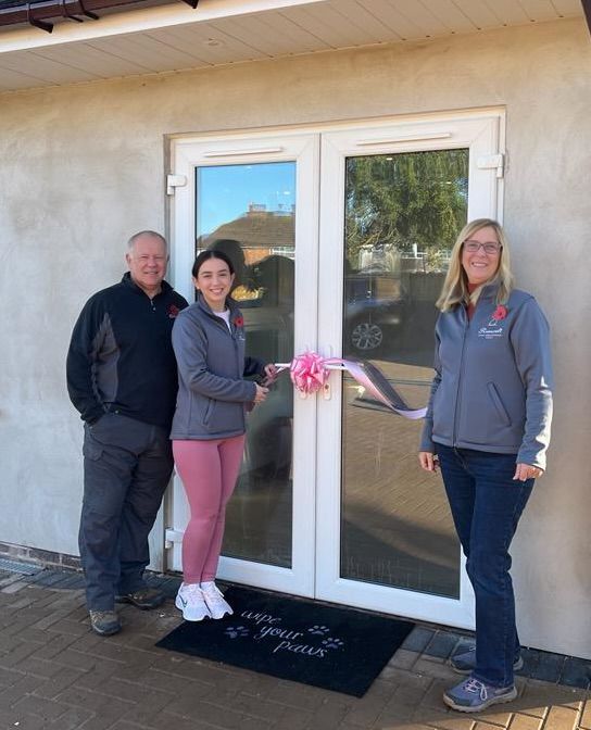 The Rosecroft team cutting a pink ribbon on a door, opening a dog hydrotherapy centre.