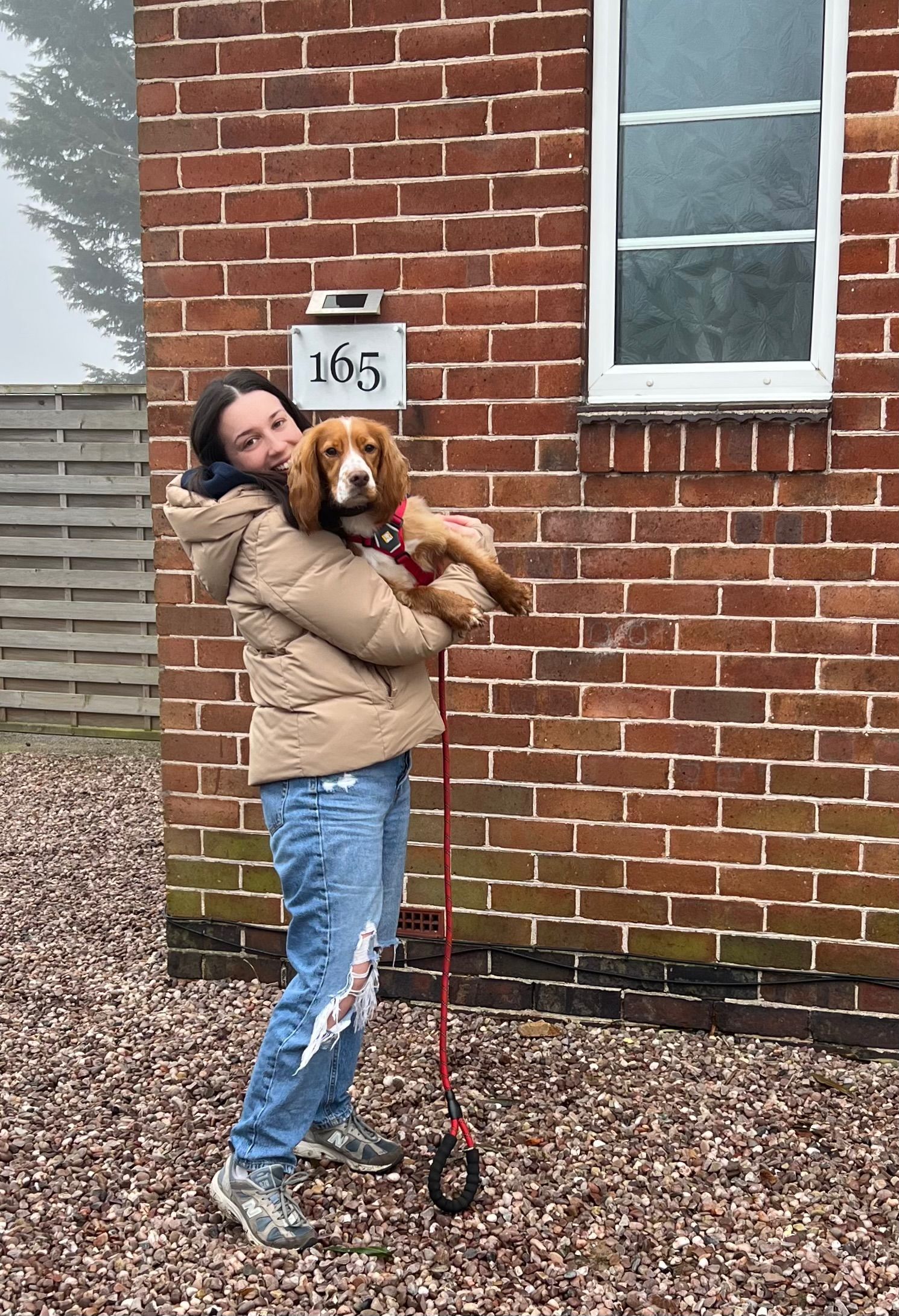 A Canine Hydrotherapist holding a cocker spaniel outside of a dog hydrotherapy centre.