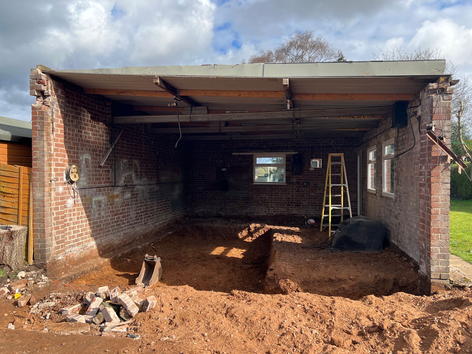 A building with a missing wall and a dug out hole for a canine hydrotherapy pool.