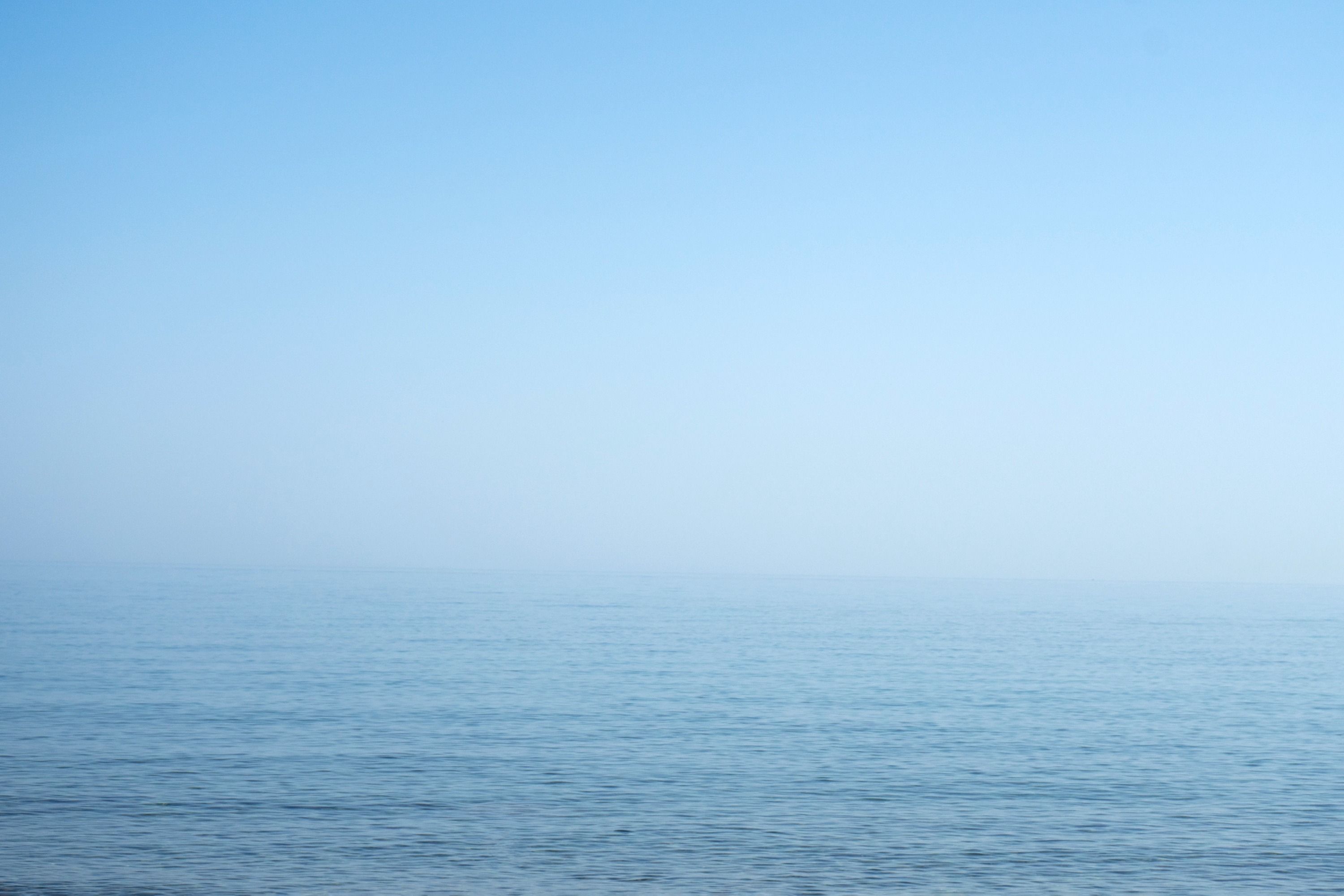 A landscape of a calm blue sea on a foggy day